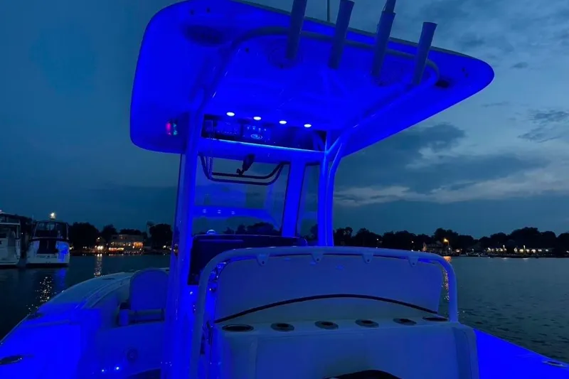 Slide: The Image of 2021 Sea Hunt Ultra 275 SE boat illuminated with blue lights at dusk on the water. - 3