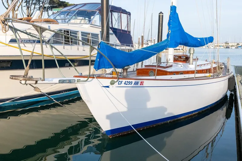 Slide: The Image of 1938 Philip Rhodes Cutter sailboat docked with blue covers and wooden details. - 13