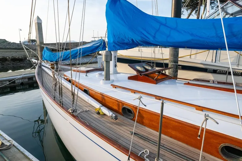 Slide: The Image of Vintage 1938 Philip Rhodes Cutter sailboat with blue sail cover docked at marina. - 15