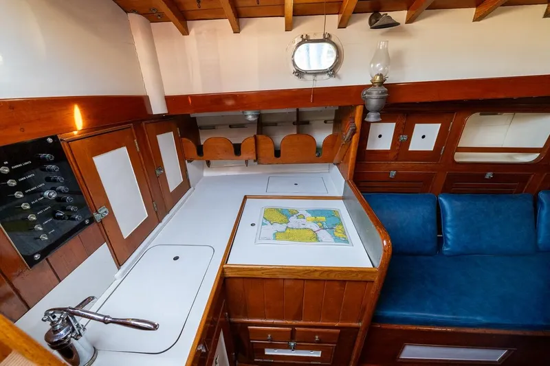 Slide: The Image of Interior of a 1938 Philip Rhodes Cutter, featuring a classic wooden design and nautical map. - 52