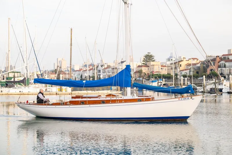 Slide: The Image of Classic 1938 Philip Rhodes Cutter sailboat docked in a marina, featuring blue sails. - 7
