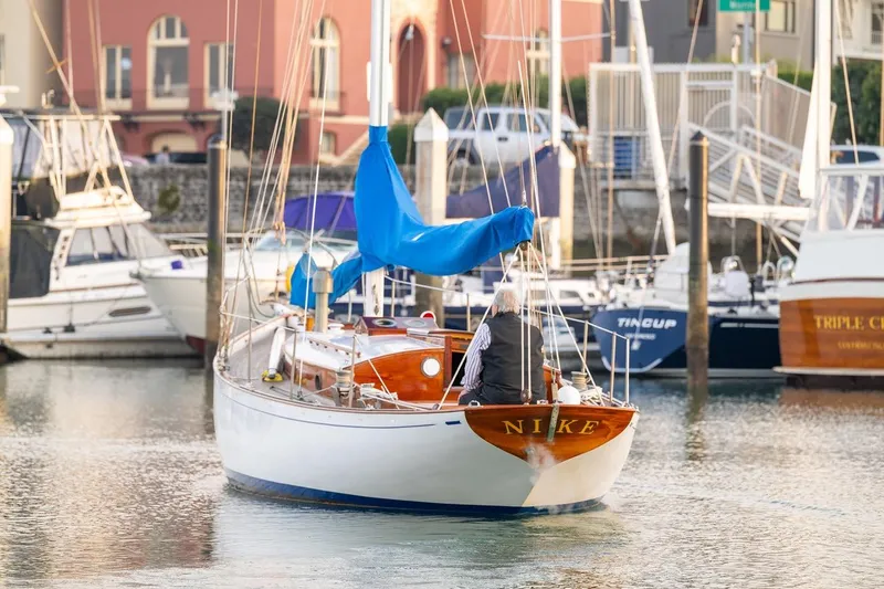 Slide: The Image of Vintage 1938 Philip Rhodes Cutter sailboat in marina, featuring wooden design and blue sail. - 8