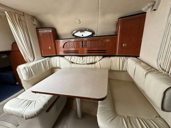 Slide: The Image of Interior of 2002 Sea Ray 280 Sundancer with cream seating and wooden cabinets. - 18