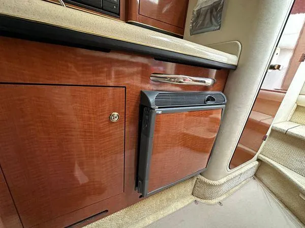Slide: The Image of 2002 Sea Ray 280 Sundancer interior with wood cabinetry and compact refrigerator. - 20