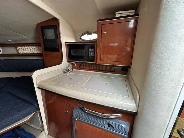Slide: The Image of 2002 Sea Ray 280 Sundancer cabin with kitchenette, featuring sink, microwave, and storage cabinets. - 22