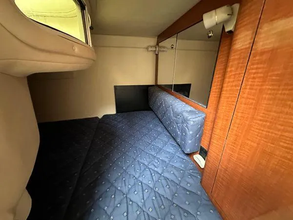 Slide: The Image of 2002 Sea Ray 280 Sundancer cabin interior with blue bedding and wood paneling. - 23