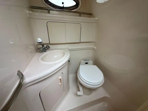 Slide: The Image of 2002 Sea Ray 280 Sundancer bathroom with sink, toilet, and storage cabinets. - 24