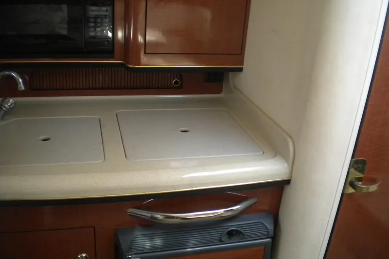 Slide: The Image of 2002 Sea Ray 280 Sundancer galley with sink, countertop, and microwave. - 26
