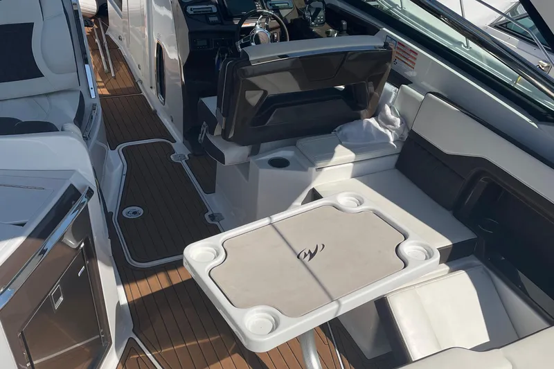 Slide: The Image of 2018 Monterey 328 Super Sport boat interior with seating and table, featuring sleek design and wood flooring. - 11