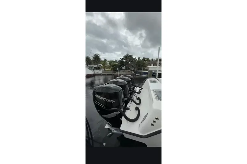Slide: The Image of 2020 Contender 39 ST boat with multiple Mercury outboard engines docked by palm trees. - 11