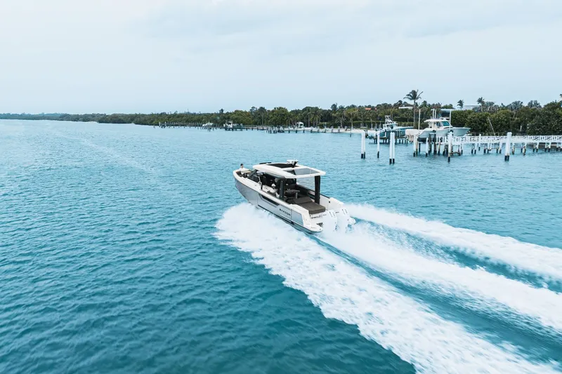 Slide: The Image of A 2027 Saxdor 400 GTO speeds across blue water, surrounded by a tranquil harbor. - 37