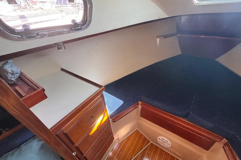 Slide: The Image of 1988 Catalina 34 sailboat interior with wooden cabinetry and cozy sleeping area. - 10