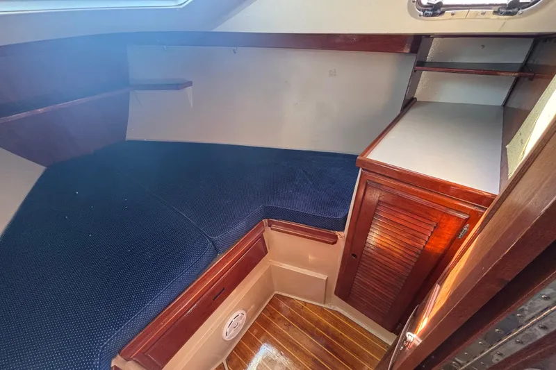 Slide: The Image of 1988 Catalina 34 yacht interior with blue cushioned berth and wooden cabinetry. - 11