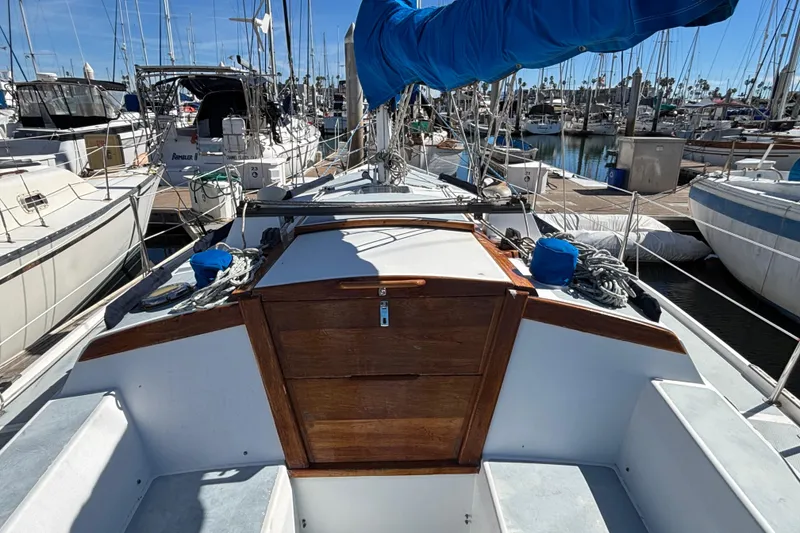 Slide: The Image of 1988 Catalina 34 sailboat docked at marina, featuring wooden hatch and blue sail cover. - 35