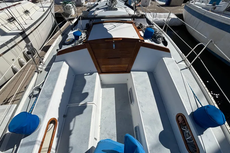 Slide: The Image of 1988 Catalina 34 sailboat cockpit with wooden hatch and blue cushions at marina. - 40