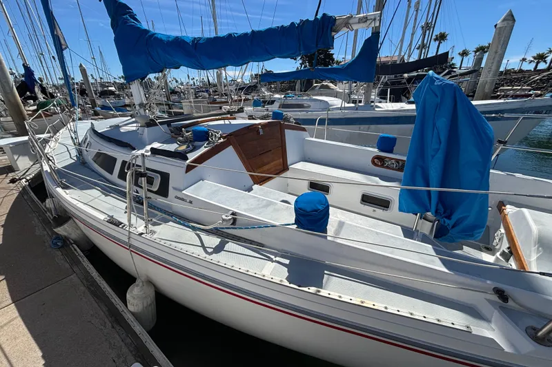 Slide: The Image of 1988 Catalina 34 sailboat docked at marina, featuring blue sail covers and clean deck. - 43