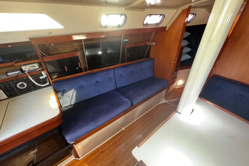 Slide: The Image of Interior of a 1988 Catalina 34 sailboat with blue seating and wooden accents. - 5