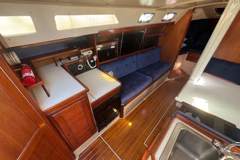 Slide: The Image of 1988 Catalina 34 yacht interior with wood finish, blue seating, and navigation equipment. - 6
