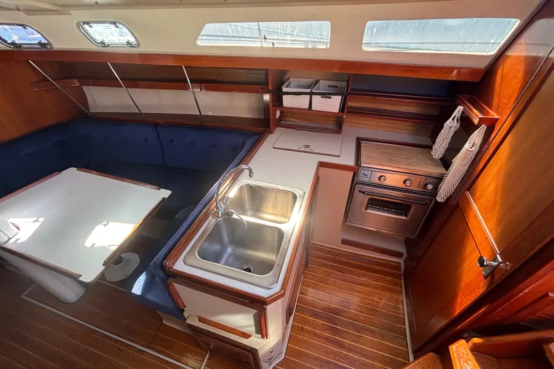 Slide: The Image of 1988 Catalina 34 yacht interior with kitchen, dining area, and wooden finishes. - 7