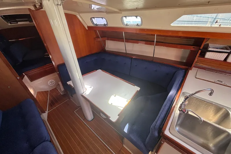Slide: The Image of Interior of a 1988 Catalina 34 sailboat with cozy seating and a compact kitchen area. - 8