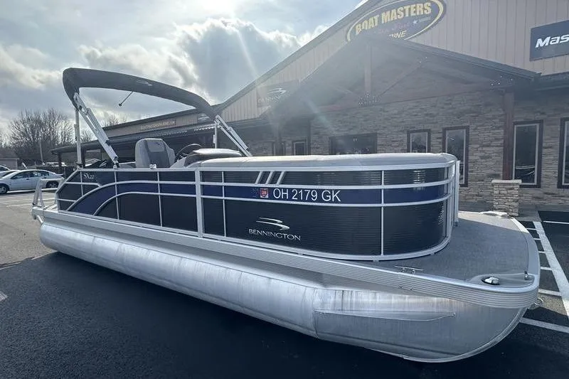 Slide: The Image of 2023 Bennington 22 SX Swingback pontoon boat parked outside dealership. - 4