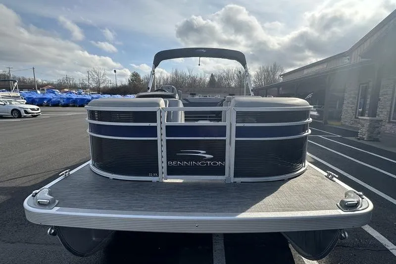 Slide: The Image of 2023 Bennington 22 SX Swingback pontoon boat parked outdoors on a cloudy day. - 5