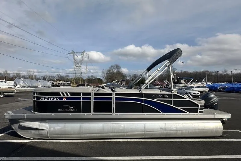 Slide: The Image of 2023 Bennington 22 SX Swingback pontoon boat parked outdoors on a cloudy day. - 6