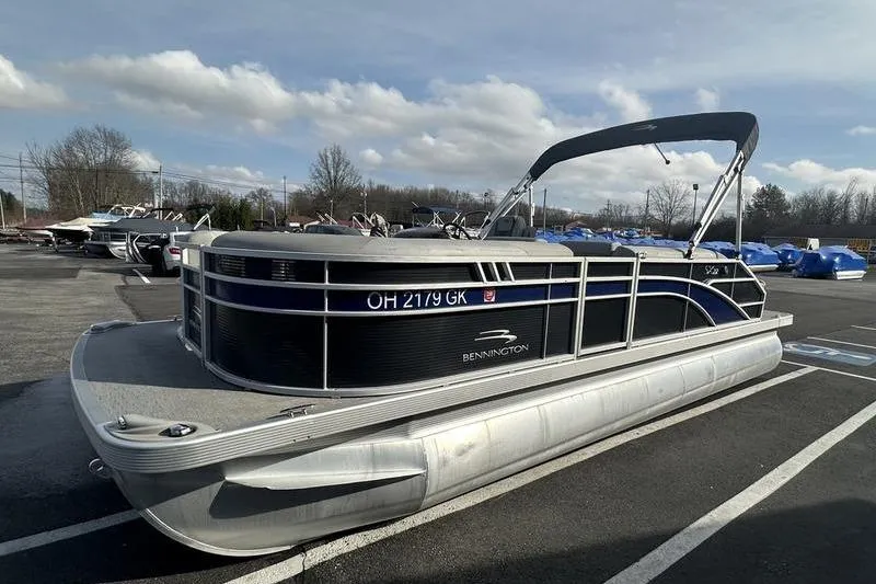 Slide: The Image of 2023 Bennington 22 SX Swingback pontoon boat parked in a lot under a cloudy sky. - 7