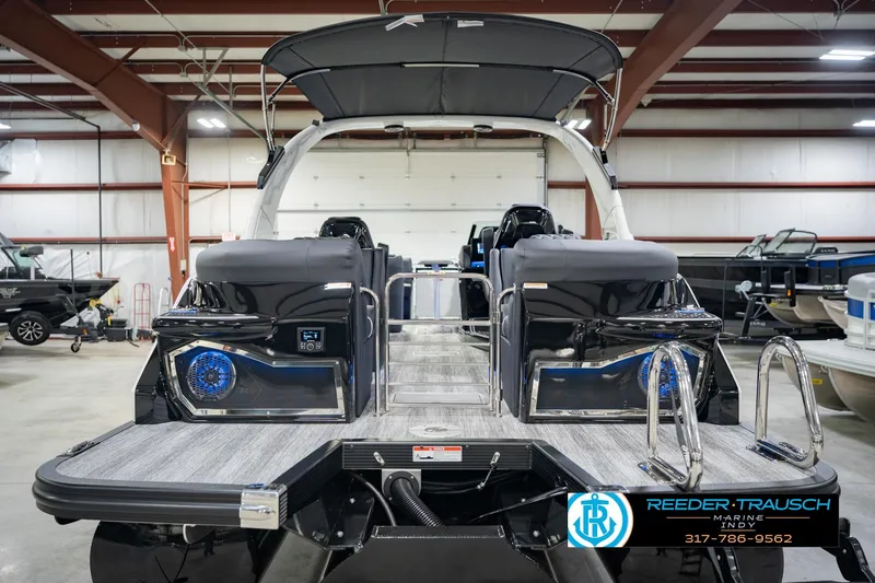 Slide: The Image of 2026 Bennington QX 25 QXFBA pontoon boat in showroom, rear view with sleek design. - 9