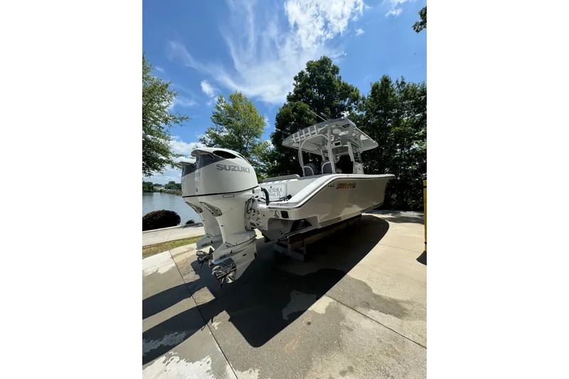 Slide: The Image of 2024 Sea Pro 322 Offshore boat with Suzuki outboard motor, docked near a scenic lake. - 10