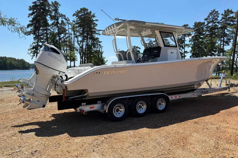 Slide: The Image of 2024 Sea Pro 322 Offshore boat on trailer by a lake, featuring dual Suzuki engines. - 2