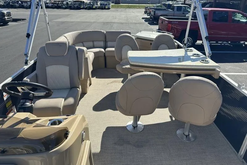 Slide: The Image of 2018 Bennington 23 SPDX pontoon boat interior with beige seating and table setup. - 21