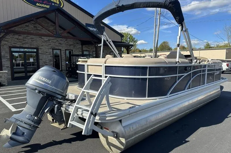 Slide: The Image of 2018 Bennington 23 SPDX pontoon boat with Yamaha motor, parked outside a marine dealership. - 3