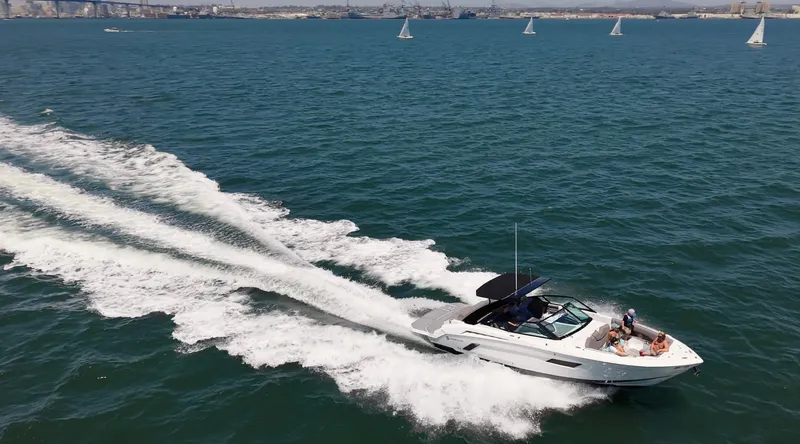 Slide: The Image of A 2019 Cruisers Yachts 338 CX South Beach Bow Rider speeds across the sea, surrounded by sailboats. - 0