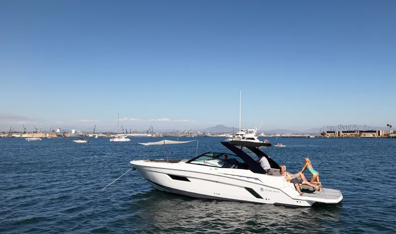 Slide: The Image of A white sport boat with a black roof cruises on calm water. Two people relax on board. - 4