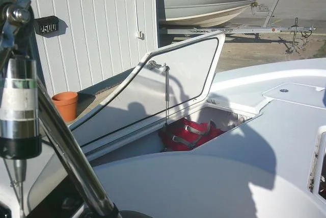 Slide: The Image of 2017 Sportsman Masters 207 Bay Boat with open storage compartment and visible red life jackets. - 15