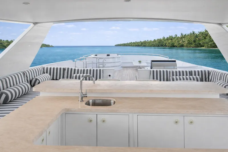 Slide: The Image of Luxurious Ocean Alexander 120 Megayacht deck with striped seating, ocean view, and tropical backdrop. - 60