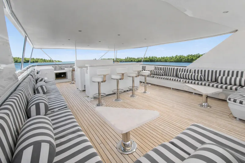Slide: The Image of Luxurious Ocean Alexander 120 Megayacht deck with striped seating, ocean view, and tropical backdrop. - 62