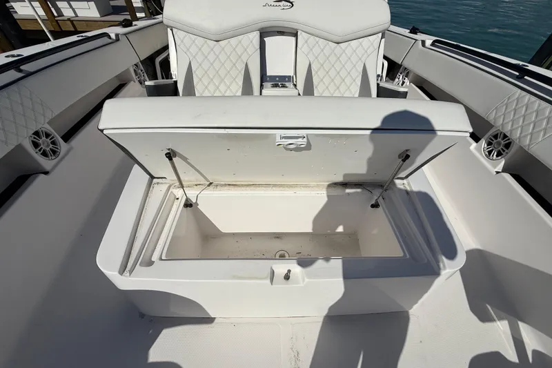 Slide: The Image of Open storage compartment on a 2020 Streamline 45 boat, featuring quilted seating and marine speakers. - 20