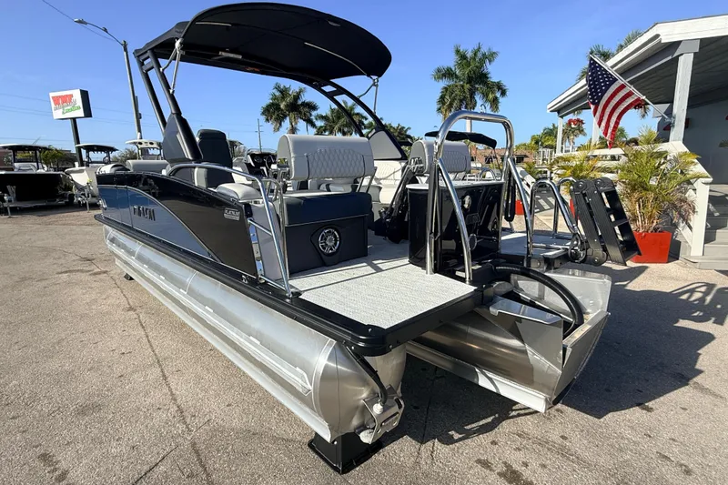 Slide: The Image of 2026 Avalon 2385 Catalina Quad Lounger, Tri Toon, high-performance boat in sunny dealership setting. - 8