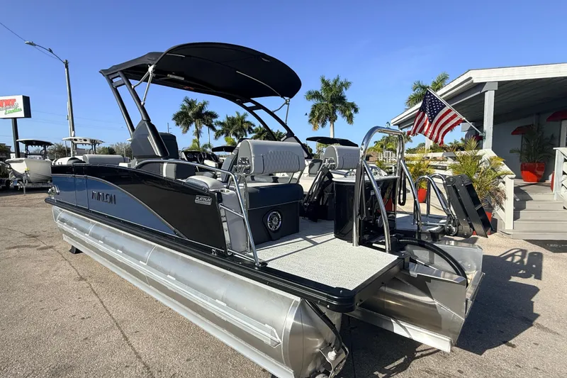 Slide: The Image of 2026 Avalon 2385 Catalina Quad Lounger Tri Toon boat with American flag, parked outdoors. - 9