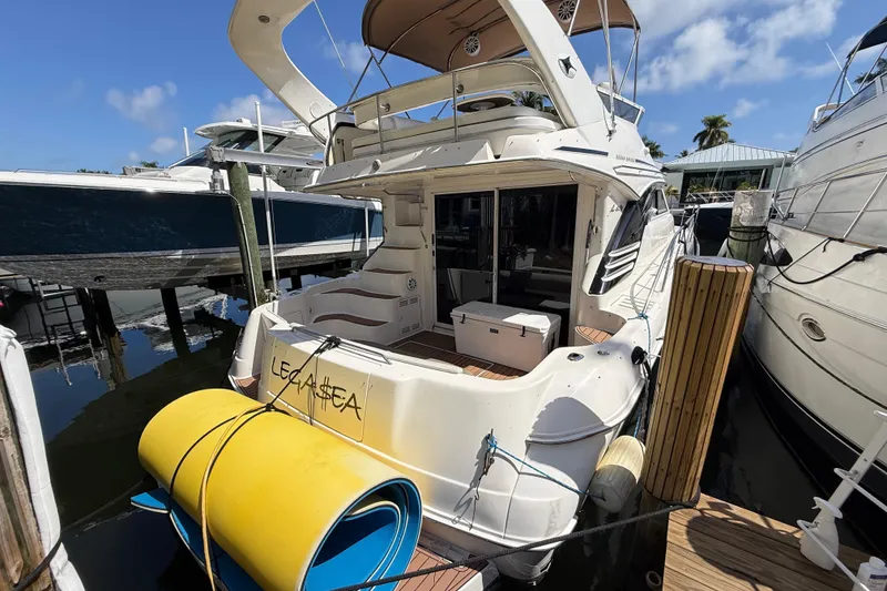 Slide: The Image of 1998 Sea Ray 400 Sedan Bridge yacht docked at marina, rear view with blue sky. - 2