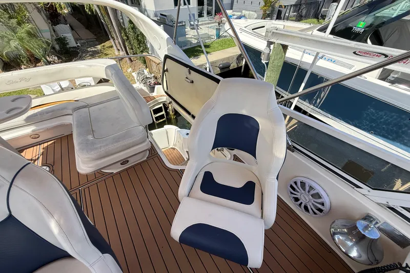 Slide: The Image of 1998 Sea Ray 400 Sedan Bridge interior with white and blue seating, wooden deck. - 23