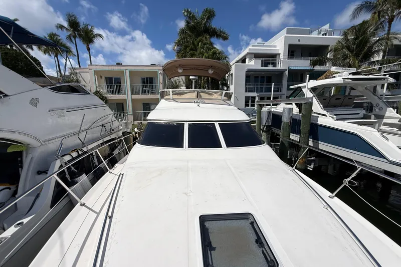 Slide: The Image of 1998 Sea Ray 400 Sedan Bridge yacht docked between luxury boats, under a clear blue sky. - 3