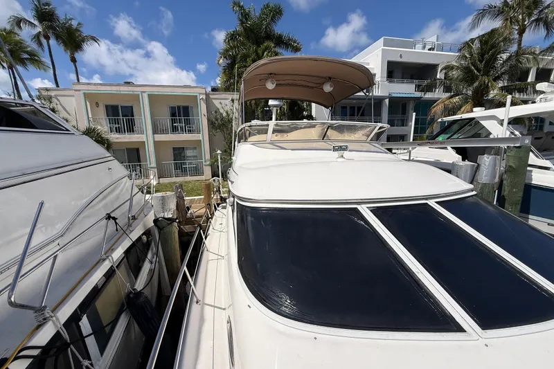 Slide: The Image of 1998 Sea Ray 400 Sedan Bridge yacht docked near palm trees and buildings. - 4