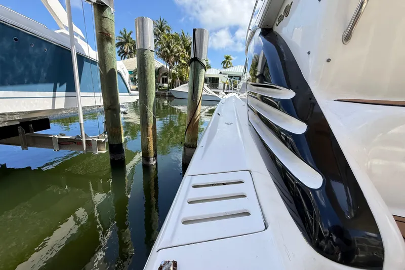 Slide: The Image of 1998 Sea Ray 400 Sedan Bridge docked near wooden pilings, with clear water and palm trees. - 8