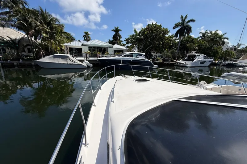 Slide: The Image of 1998 Sea Ray 400 Sedan Bridge yacht docked in a scenic marina with palm trees. - 9