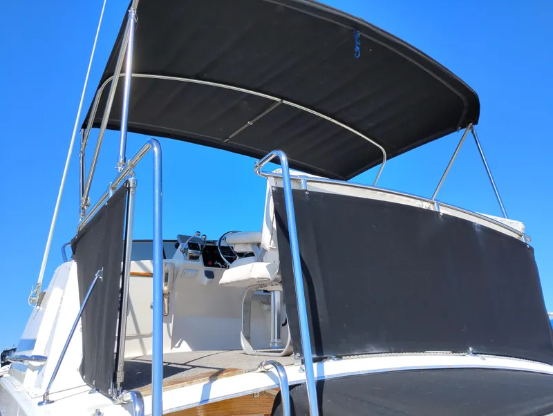 Slide: The Image of 1978 Bertram 33 Convertible boat with canopy and helm, under clear blue sky. - 11