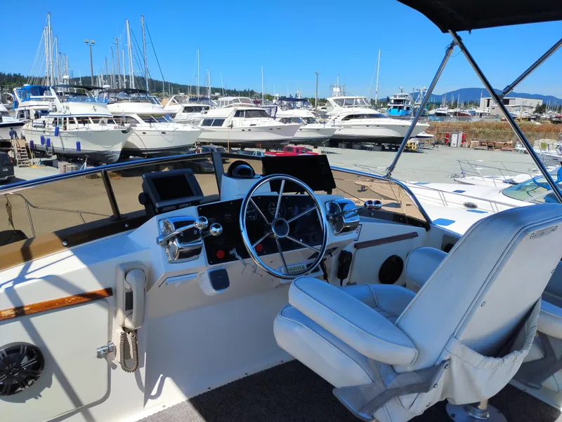 Slide: The Image of 1978 Bertram 33 Convertible yacht helm with marina view, featuring steering wheel and controls. - 12
