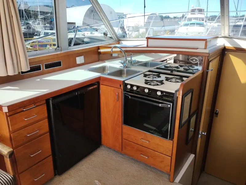 Slide: The Image of 1978 Bertram 33 Convertible yacht kitchen with stove, sink, and wooden cabinetry. - 23